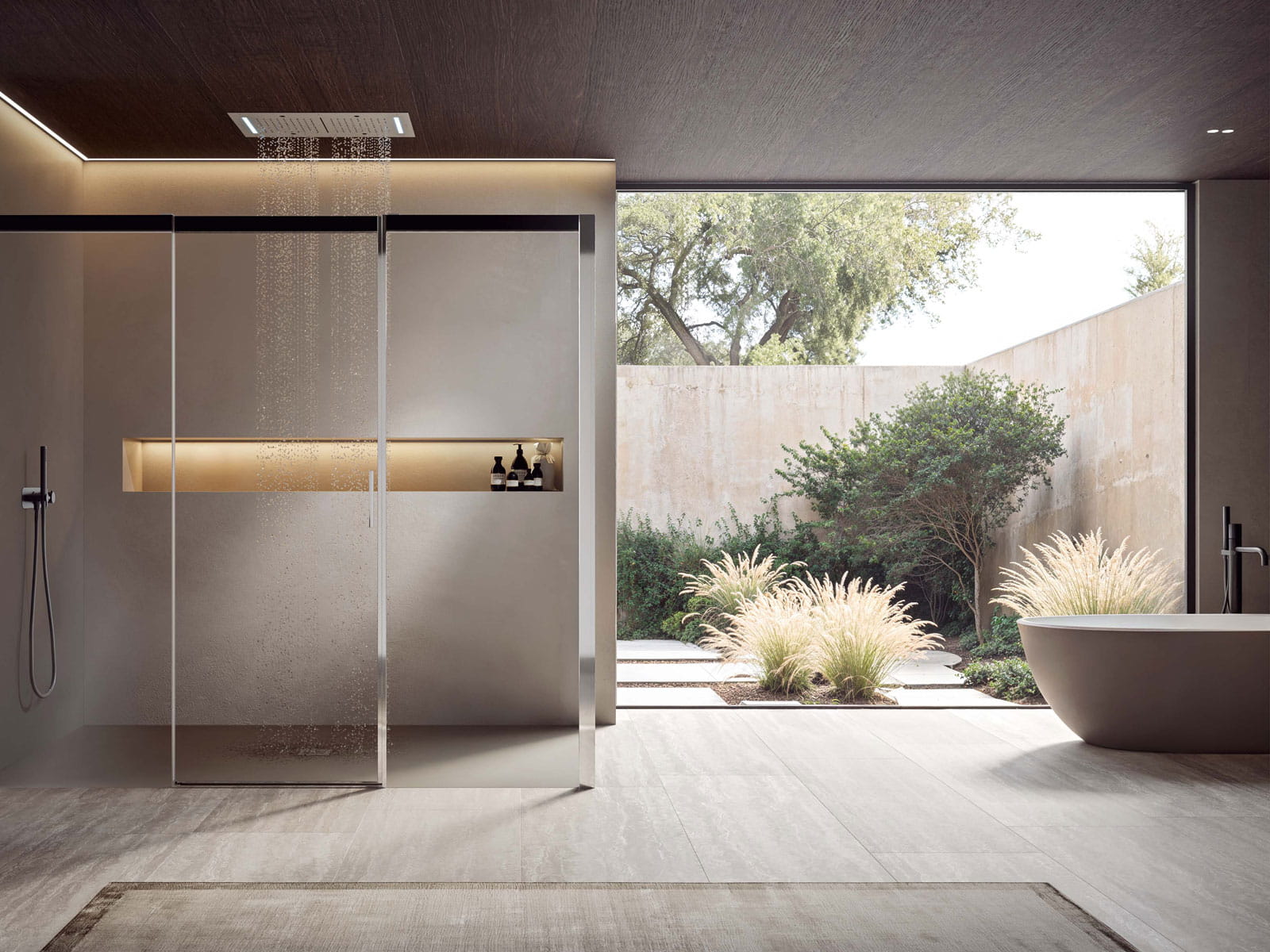 Doccia a filo pavimento con soffione a soffitto e nicchia illuminata, vasca freestanding davanti alla vetrata sul giardino