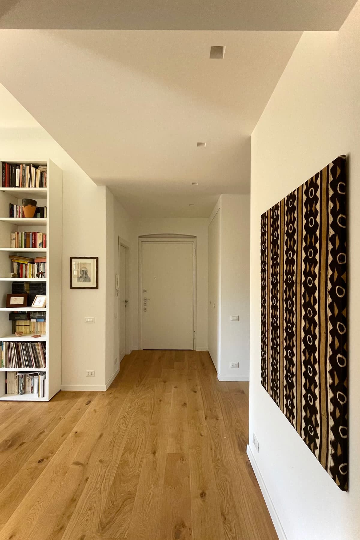 Ingresso con parquet in rovere, libreria bianca e porta blindata laccata
