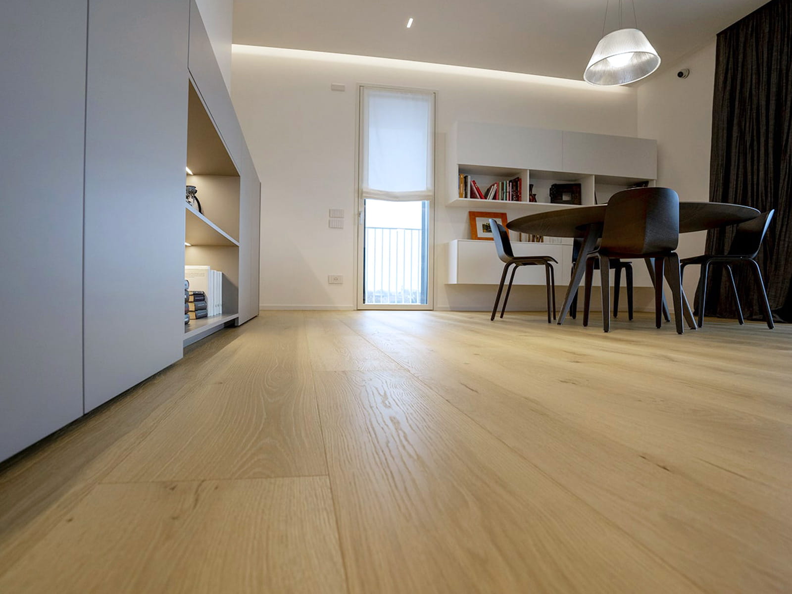 Zona pranzo con parquet in rovere chiaro a plance lunghe e larghe, mobili bianchi su misura