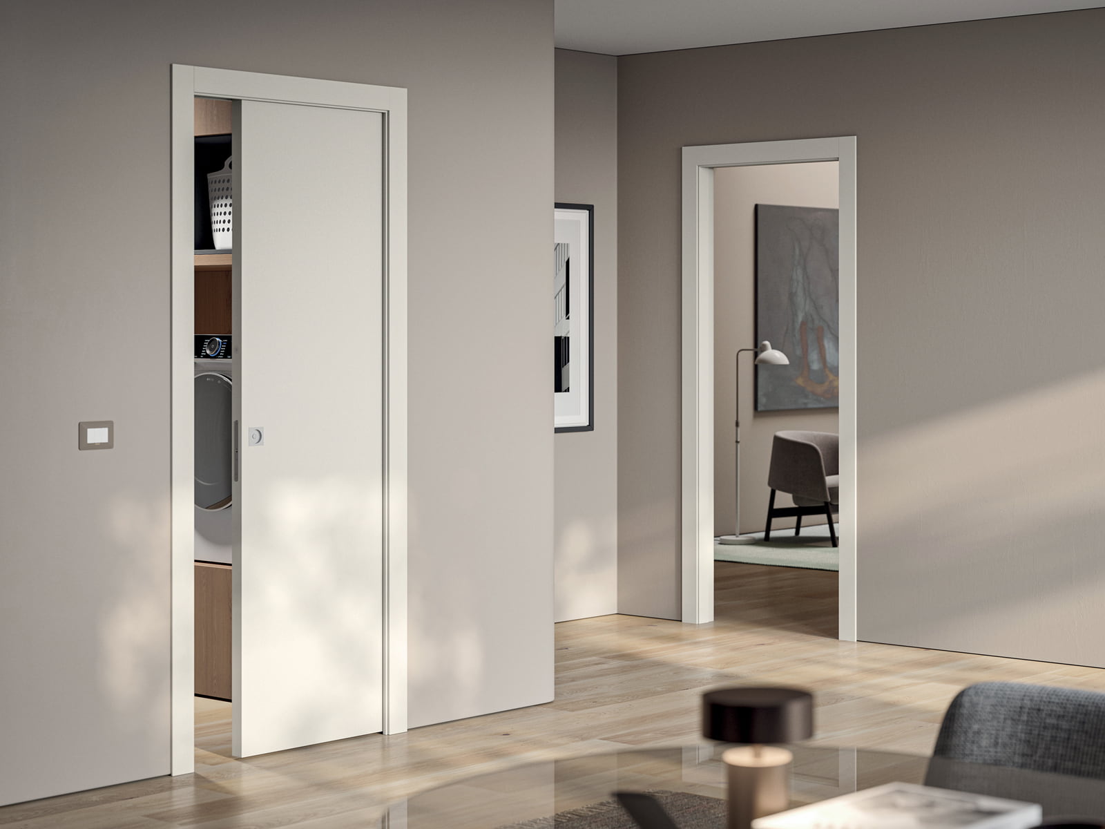 Porta scorrevole interno muro bianca, semiaperta sulla lavanderia, con parquet in rovere chiaro